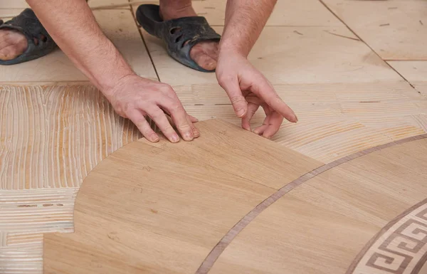 The carpenter installs one of the decorative elements of the parquet. — Stock Photo, Image