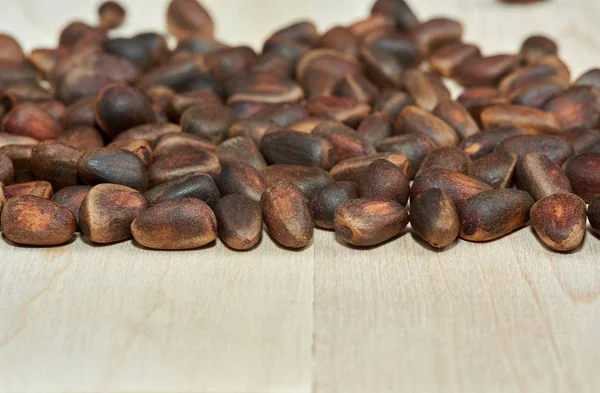 A scattering of pine nuts on the background of boards made of maple.