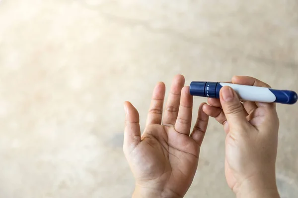 Close up of woman hands using lancet on finger to check blood su — Stock Photo, Image