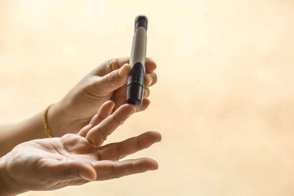 Close up of woman hands using lancet on finger to check blood su — Stock Photo, Image