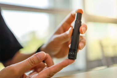 Kan suga kontrol etmek için parmak lancet kullanarak adam ellerini yakın