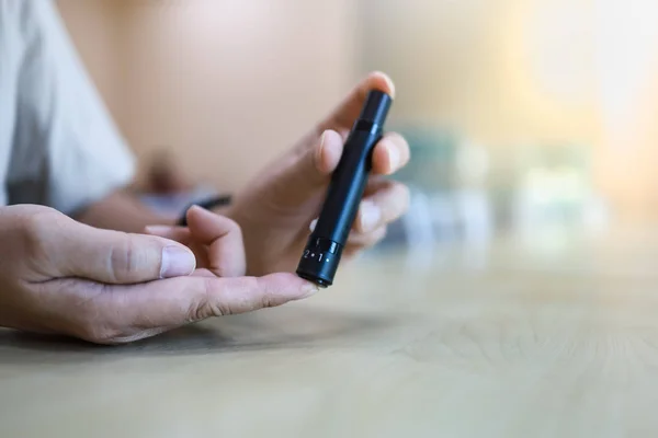 Close up of man hands using lancet on finger to check blood suga — Stock Photo, Image