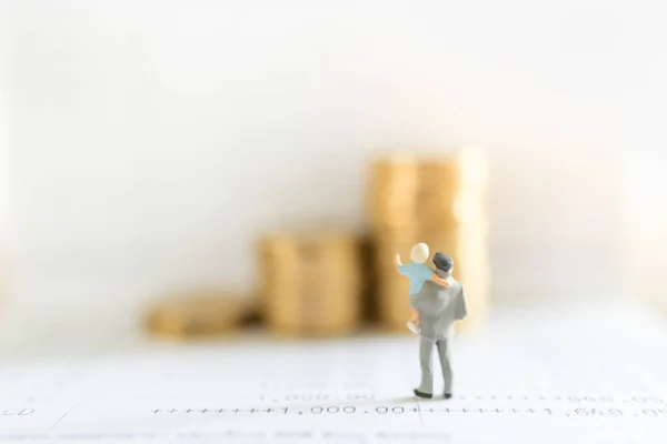 Business, Money, Saving, Security and Family Concept. Close up of father and child standing on bank passbook and looking to stack of gold coins with copy space.