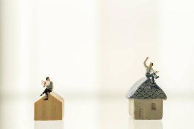 Coronavirus 2019 (COVID-19) için Sığınak, Ev ve Sosyal Mesafe Konsepti (Home and Work from Coronavirus 2019). İki iş adamı minyatür figür insanlar oturup gazete okuyor ve mini ev oyuncaklarının fotokopi alanlarında konuşuyorlar..