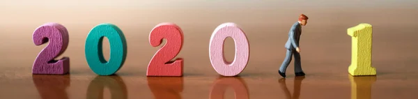 2020 to 2021 New year, Business and Planning Cover page Concept. Close up of businessman  miniature people figure walking with colorful wooden number on wooden table.