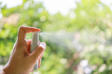 Sağlık, Sağlık, Corona Virüsü (COVID-19) ve Mikrop Koruma Konsepti. İnsanların el ele tutuşması ve küçük bir şişe alkolü püskürtmesi% 70 yeşil doğayla örtüşüyor ve uzayı kopyalıyor..