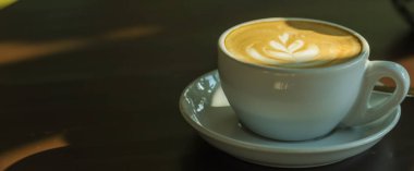 Beyaz fincan sıcak kahveye yakın çekim sabah güneş ışığı altında süt köpüklü latte ve duvar kağıdı ya da kapak sayfası konsepti için gölge kullanımı.
