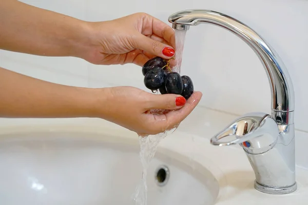 Girl washes the grapes under the tap — Stock Photo, Image