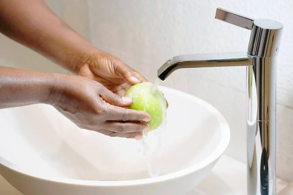 Dívku umyje jablko pod tekoucí vodou — Stock fotografie