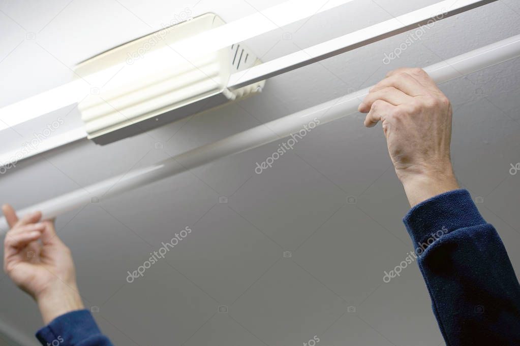 Electrician man worker installing fluorescent lamp