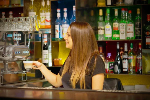 Girl bartender pours a cup of cappuccino coffee