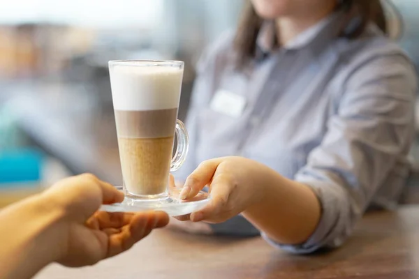 The waitress gives cappuccino to the client