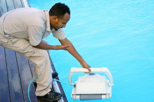 Hotel staff worker cleaning the pool