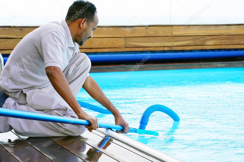 Hotel staff worker cleaning the pool