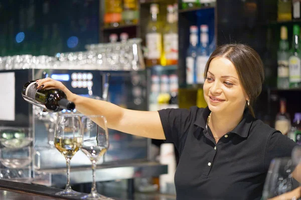 Garota barman derrama vinho em um copo de vinho — Fotografia de Stock