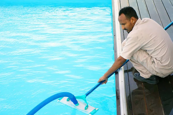 Funcionário do hotel limpando a piscina — Fotografia de Stock