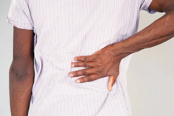 Afrikansk man, smärta i nedre delen av ryggen. — Stockfoto