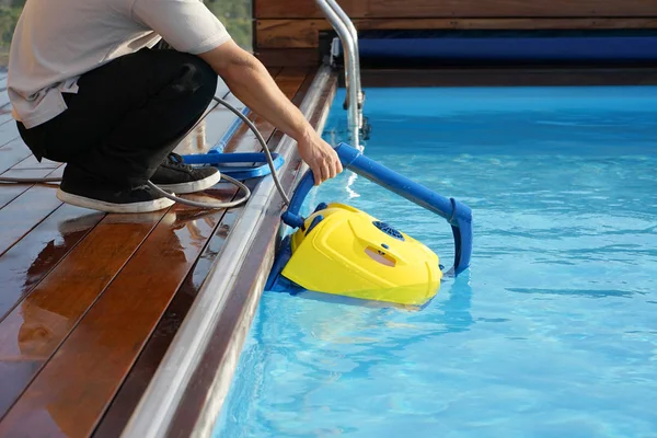 Funcionário do hotel a limpar a piscina. Limpadores de piscina automáticos . — Fotografia de Stock