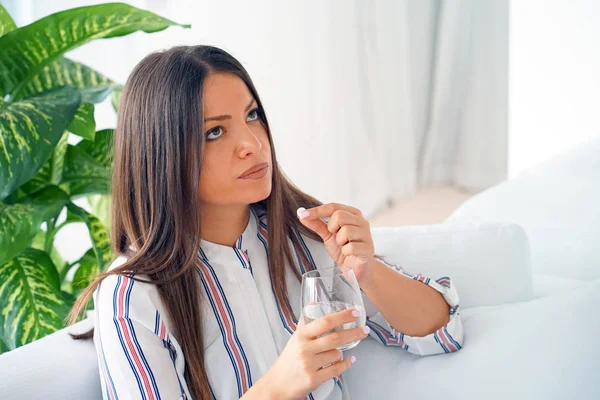 Woman drinks a pill from pain