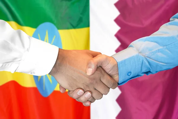 Aperto de mão no fundo da bandeira da Etiópia e Qatar . — Fotografia de Stock