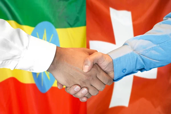 Uścisk dłoni na tle bandery Etiopii i Szwajcarii. — Zdjęcie stockowe
