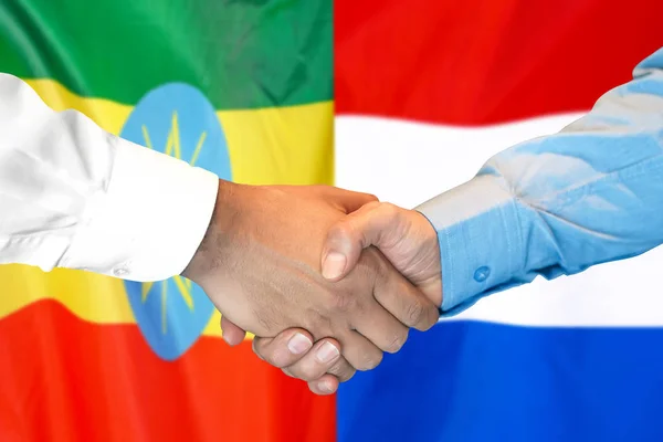 Poignée de main sur fond de drapeau éthiopien et néerlandais . — Photo