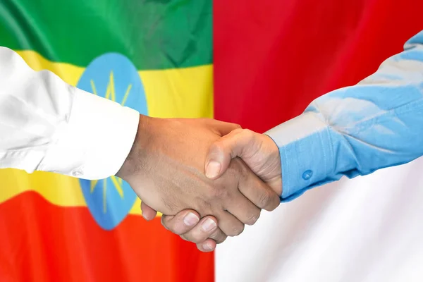 Uścisk dłoni na tle flagi Etiopii i Monako. — Zdjęcie stockowe