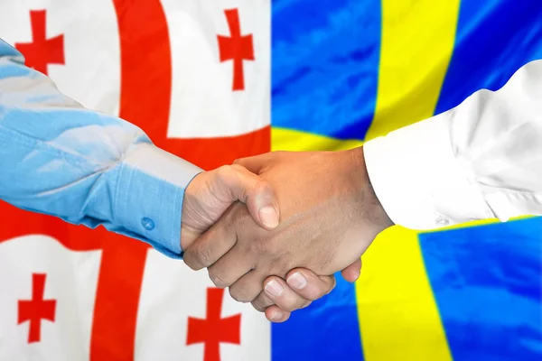 Uścisk dłoni na tle bandery Gruzji i Szwecji. — Zdjęcie stockowe