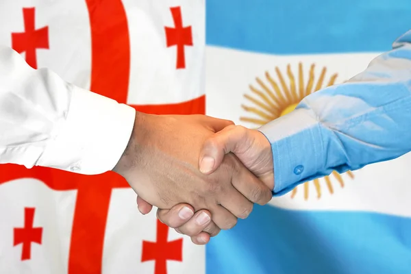 Apretón de manos sobre el fondo de la bandera de Georgia y Argentina . —  Fotos de Stock