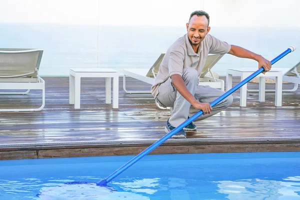 African hotel staff worker cleaning the pool