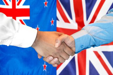 Yeni Zelanda ve Uk bayrağı arkaplanında el sıkışma.