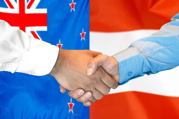 新西兰和奥地利国旗背景握手. — 图库照片