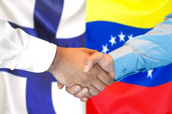 Handshake on Finland and Venezuela flag background.