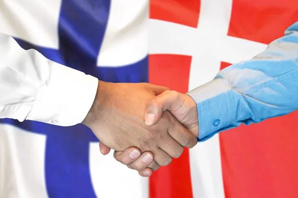 Handshake on Finland and Denmark flag background. — Stock Photo, Image