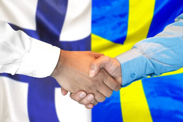 Handshake on Finland and Sweden flag background.