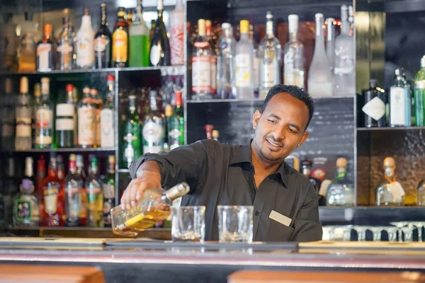 African bartender gives a glass of whiskey