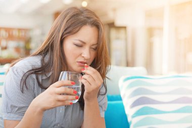 Genç bir kız bir hap acıdan içecekler.