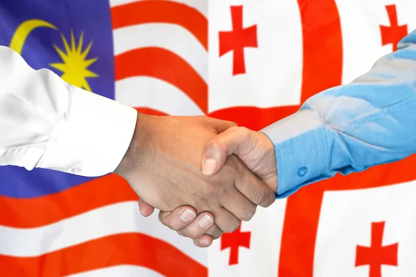 Handslag på Malaysia och Georgien flagga bakgrund. — Stockfoto