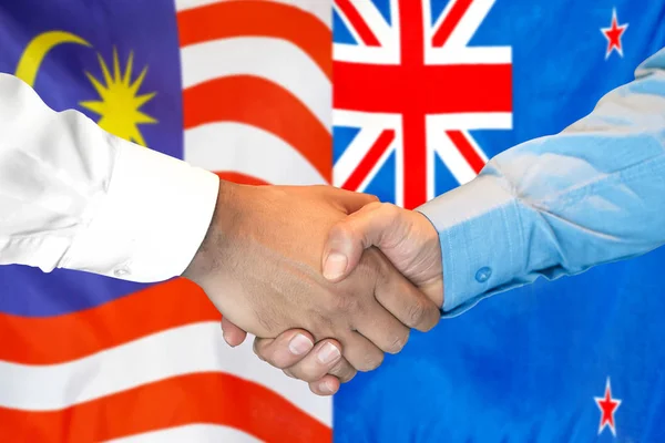 Handslag på Malaysia och Nya Zeeland flagga bakgrund. — Stockfoto