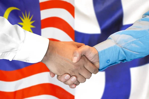 Handslag på Malaysia och Finland flagga bakgrund. — Stockfoto