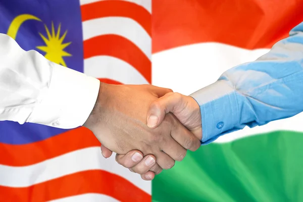 Handshake on Malaysia and Hungary flag background.