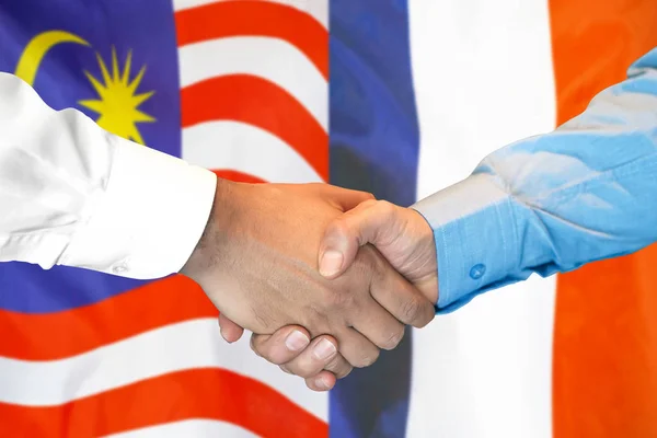 Handslag på Malaysia och Frankrike flagga bakgrund. — Stockfoto