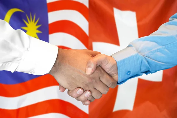 Handslag på Malaysia och Schweiz flagga bakgrund. — Stockfoto