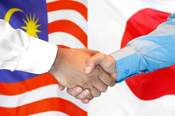 Handshake on Malaysia and Japan flag background.