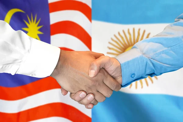 Mano apretada sobre fondo de bandera de Malasia y Argentina . —  Fotos de Stock