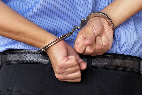 Преступные руки связаны наручниками. Крупный план
