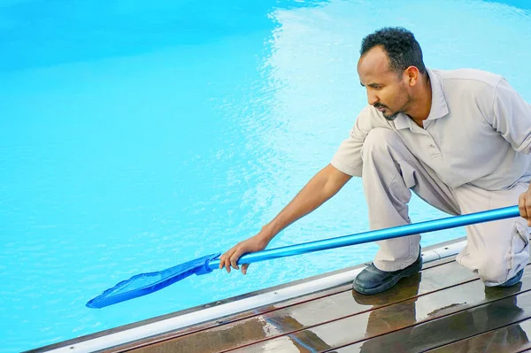 Trabajador del hotel africano limpiando la piscina — Foto de Stock