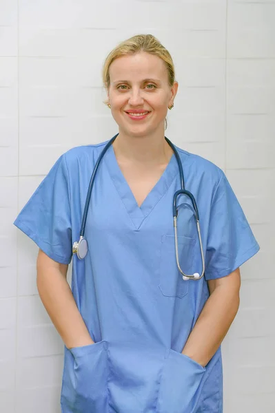 En sjuksköterska med blont hår och ett stetoskop i uniform ler mot kameran. — Stockfoto