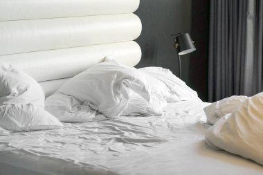 Hotel bed after use. Dirty bed pillow blanket room.