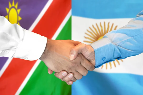 Potřesení rukou na pozadí Namibie a Argentiny vlajky. — Stock fotografie